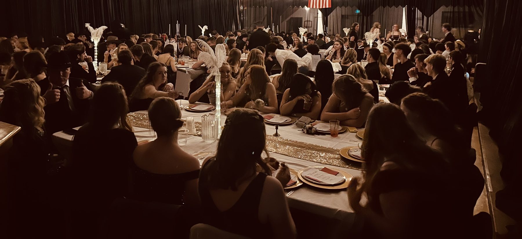 The hall set for a banquet with long tables of guests filling the room