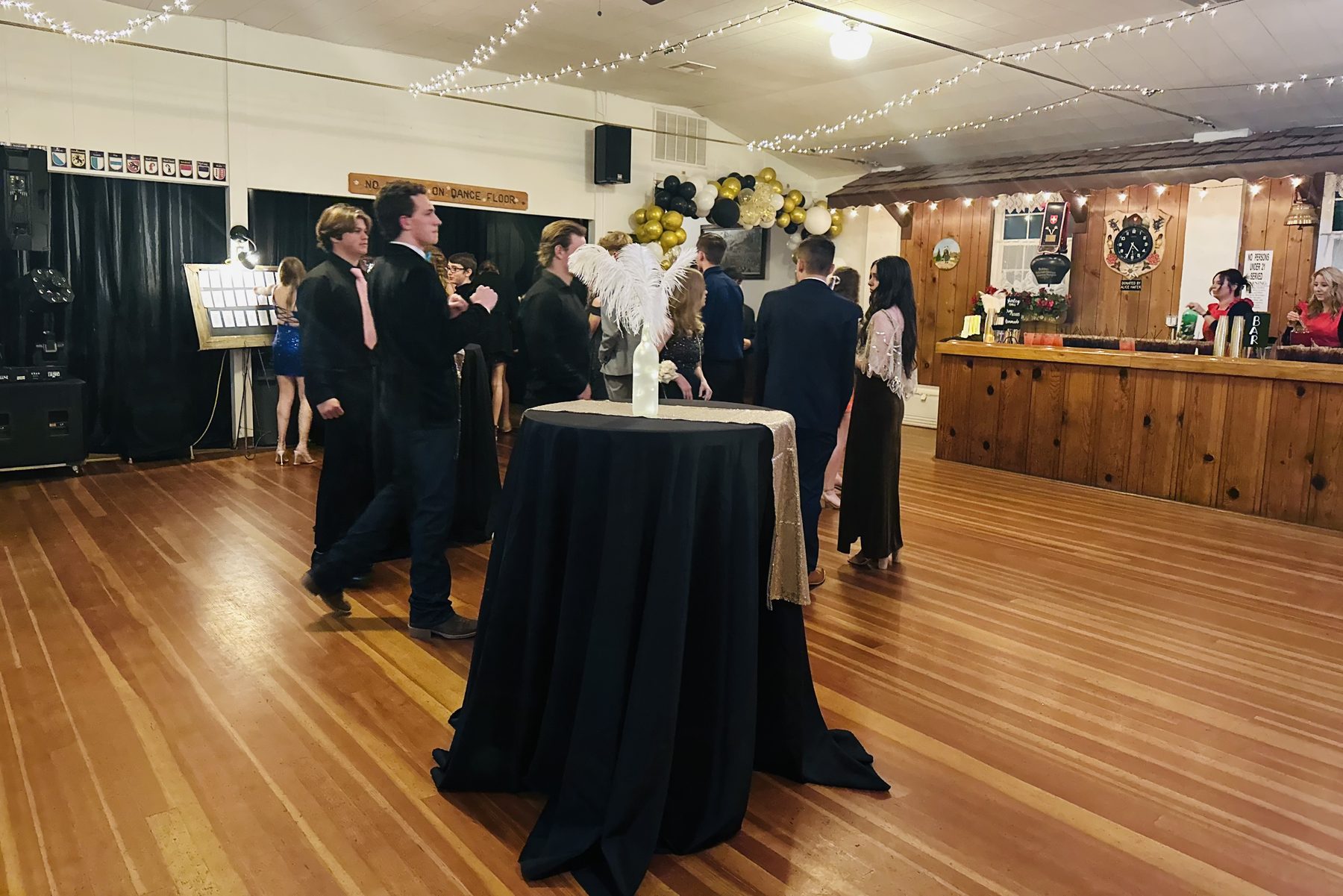 The hall dance floor with the wooden bar, cantonal crests on the wall and string lights overhead